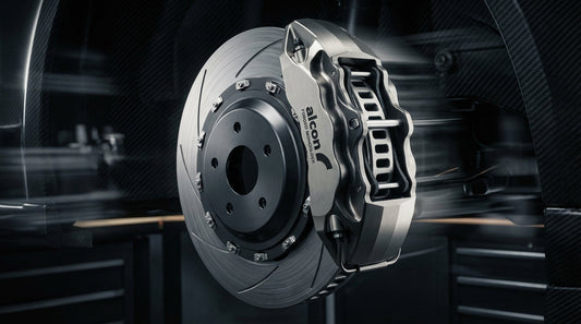 Close-up of a high-performance Alcon forged monoblock brake caliper and ventilated rotor showcasing precision automotive engineering and motorsport design.