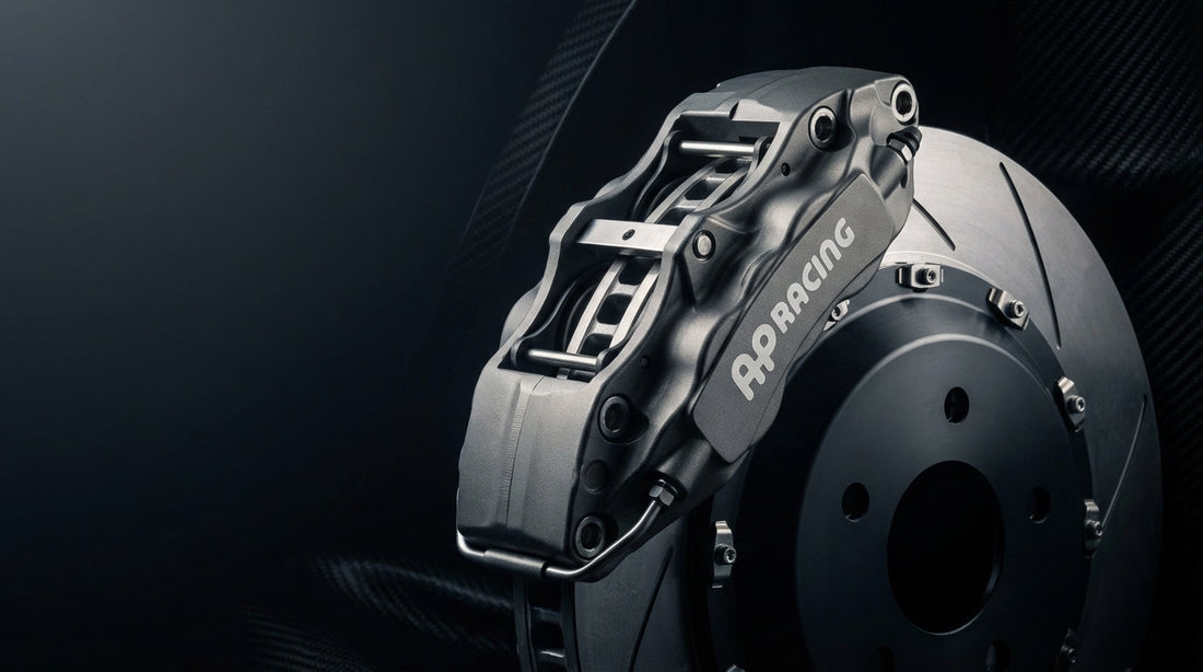A high-performance AP Racing Radi-CAL brake caliper and slotted rotor set against a dark studio background, showcasing precision motorsport engineering.