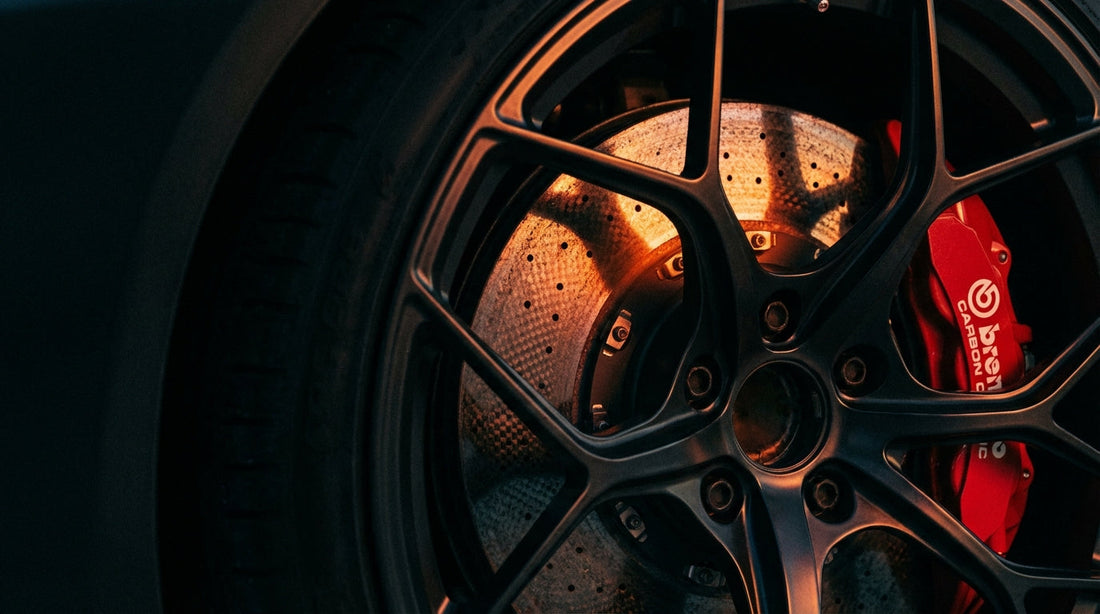 Close-up of a high-performance carbon ceramic brake rotor and caliper showing the heat-intensive bedding-in process for optimal friction.