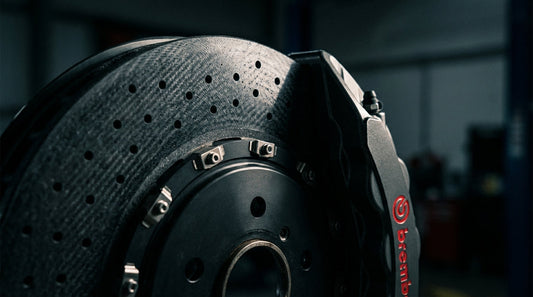 Close-up of a modern carbon ceramic brake disc and high-performance caliper on a sports car, illustrating advanced braking technology.