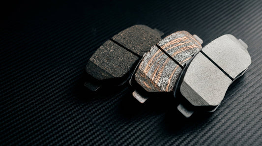 A high-detail comparison shot of ceramic, semi-metallic, and organic brake pads showcasing different material textures for automotive performance.