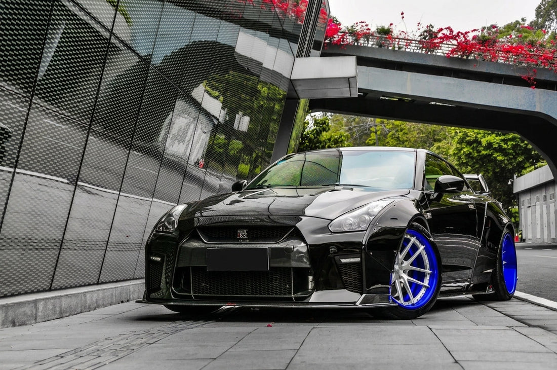 Black Nissan GT-R R35 with CMST widebody kit, transparent carbon bonnet and two-piece forged wheels, low front three-quarter hero