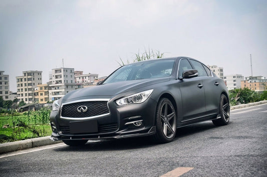 Matte black Infiniti Q50 with a CMST carbon light mod: carbon front lip, side-skirt lower lips and rear lip, front three-quarter low angle