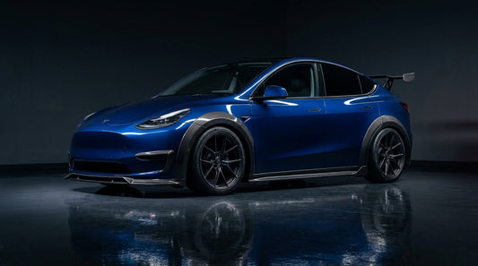 2025 Tesla Model Y Juniper widebody in deep blue with CMST carbon fibre arches, front lip and raised spoiler, 3/4 front low angle in a studio