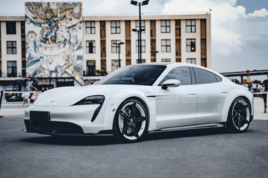 CMST widebody Porsche Taycan with carbon fibre aero kit in volcanic grey, 3/4 front low angle, studio garage lighting