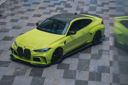 Sao Paulo Yellow BMW M4 G82 widebody wearing the CMST carbon kit, front three-quarter low angle with flared arches and visible carbon-fibre weave