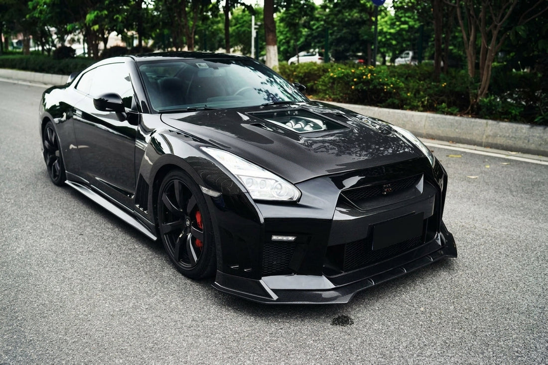 Black Nissan GT-R R35 with full CMST dry carbon-fibre kit, transparent carbon bonnet and rising rear wing, low front three-quarter hero