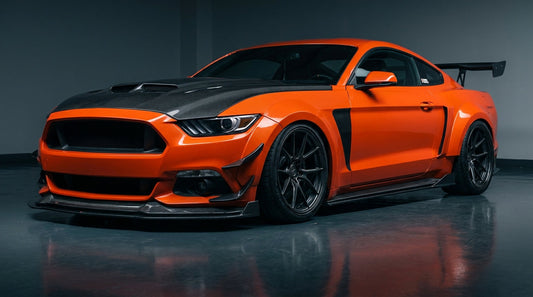 Competition-orange 2015-2017 S550 Ford Mustang wearing the CMST 17-piece dry-carbon and FRP widebody aero kit, 3/4 front low angle