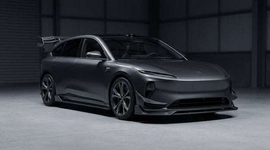 NIO ET5T shooting brake in dark grey with CMST carbon fibre aero kit, 3/4 front low angle in moody garage lighting