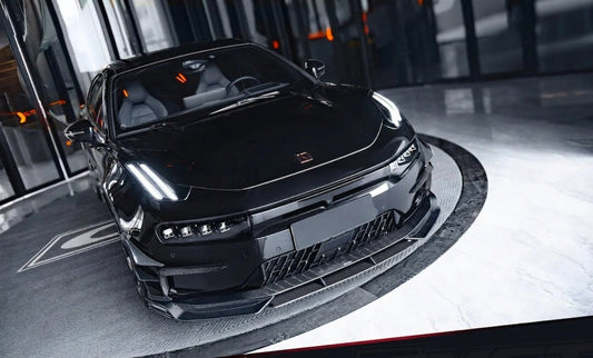 Zeekr 001 shooting-brake in white with CMST gloss carbon front lip and canard-integrated rear lip, low three-quarter front angle, studio lighting