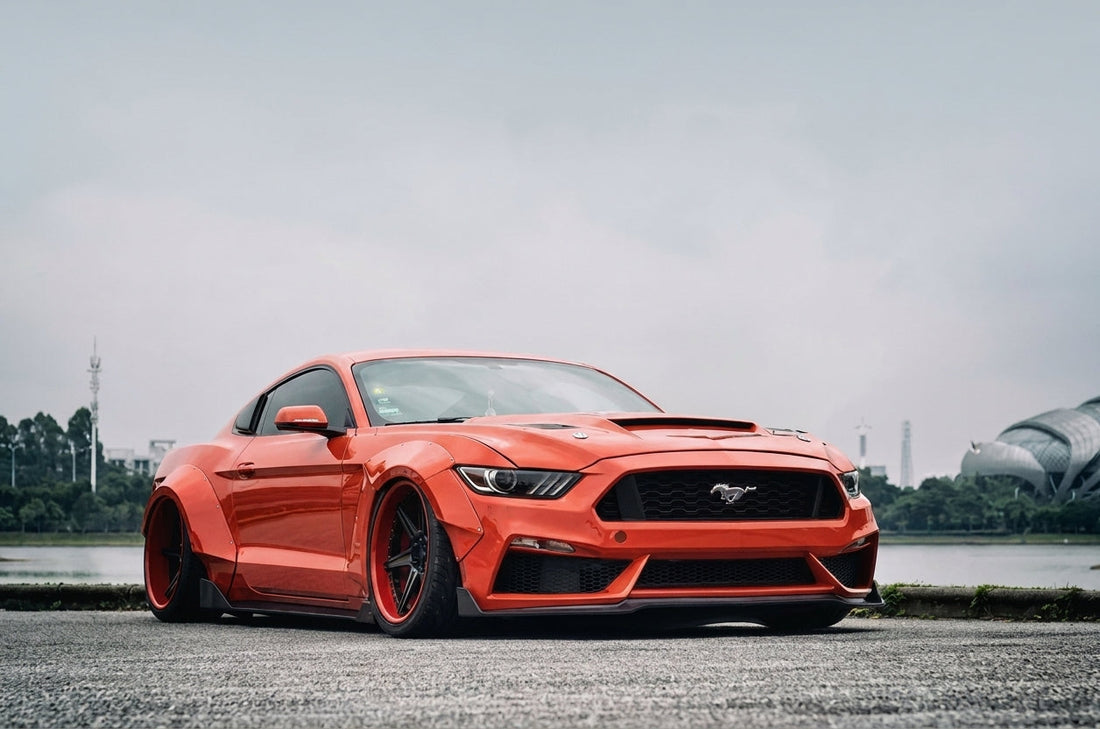 Single CMST 20-inch 2-piece forged wheel for a Ford Mustang with a gloss-black six-spoke face and a coloured outer lip with exposed lip hardware, three-quarter studio angle on a dark reflective surface