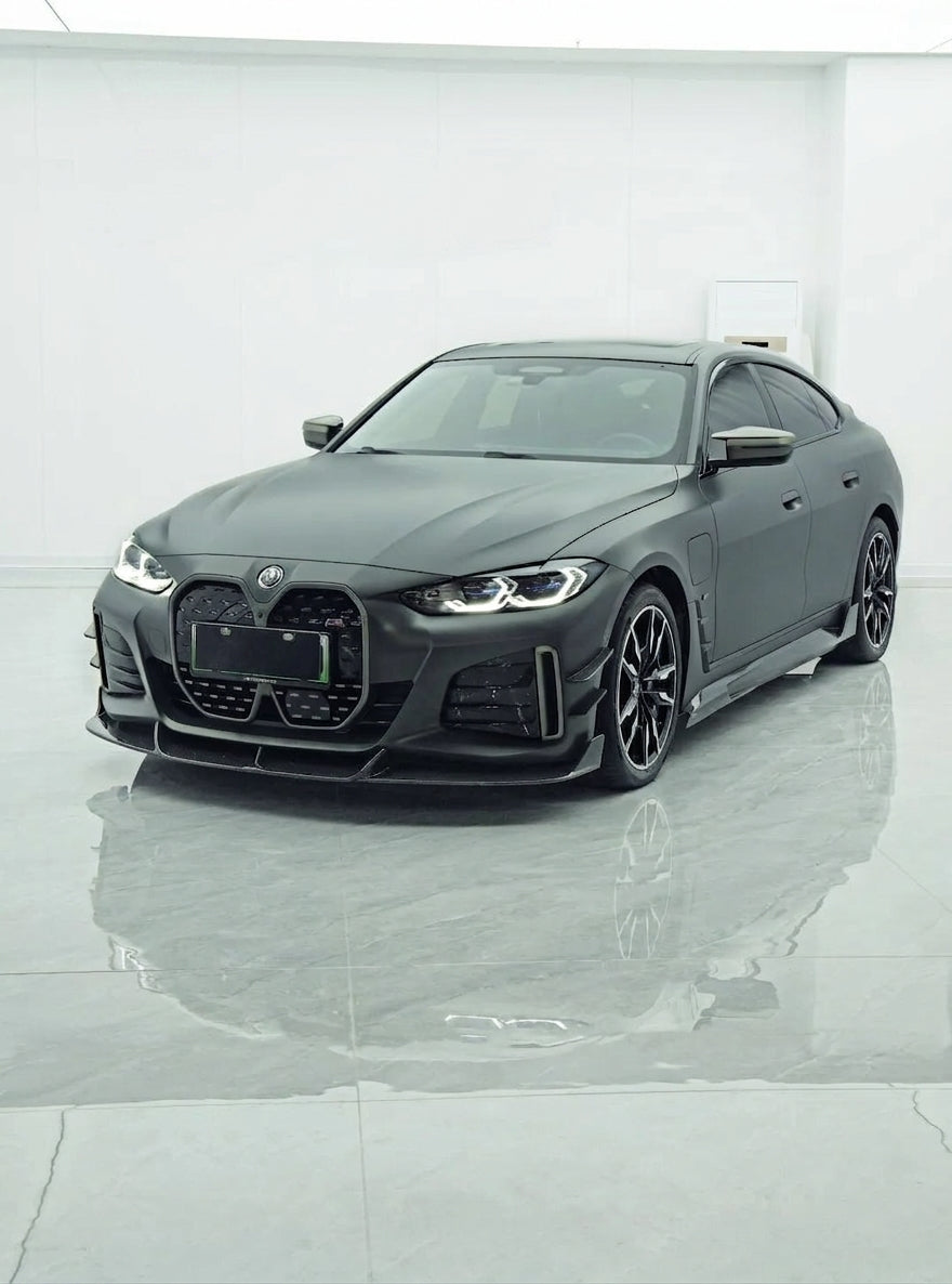 BMW i4 M50 Gran Coupe in Frozen grey wearing the full CMST dry carbon aero kit, front three-quarter low angle with visible carbon-fibre weave