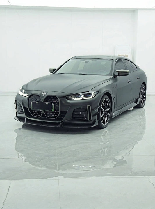 BMW i4 M50 Gran Coupe in Frozen grey wearing the full CMST dry carbon aero kit, front three-quarter low angle with visible carbon-fibre weave
