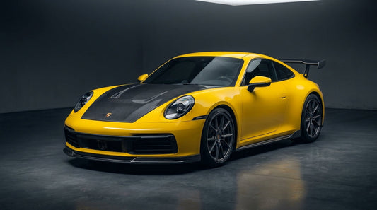 Yellow Porsche 911 992 Carrera with CMST carbon front lip, vented bonnet and rear wing in a studio
