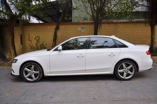 White Audi A4 saloon with CMST carbon fibre front lip, three-quarter front low angle in a studio