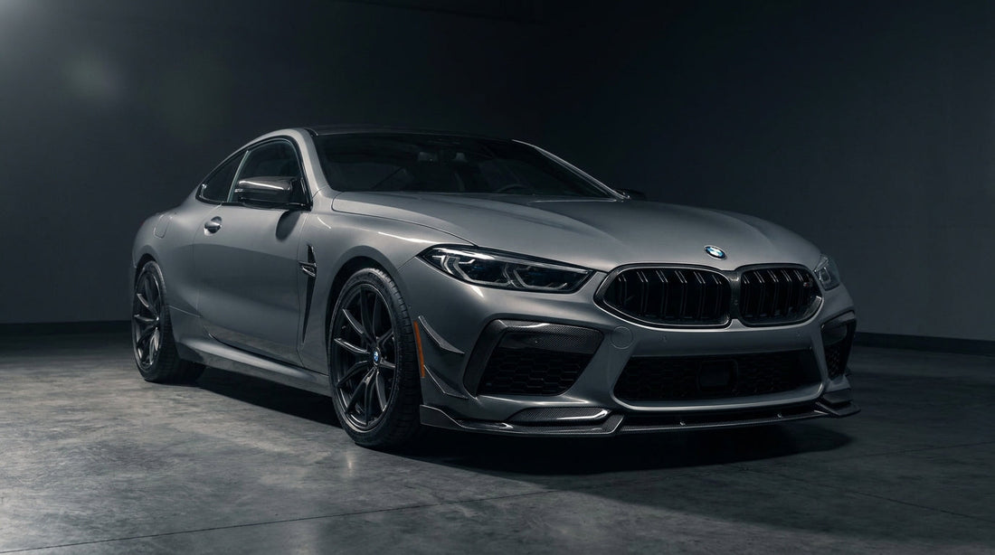 Grey BMW M8 coupe with CMST carbon front lip and carbon fenders, low front three-quarter studio shot