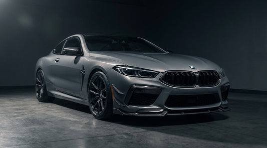 Grey BMW M8 coupe with CMST carbon front lip and carbon fenders, low front three-quarter studio shot