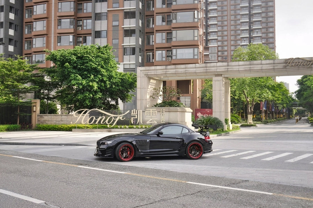 Black BMW Z4 E89 roadster in the CMST widebody carbon and FRP kit on two-piece forged wheels with red barrels and dual-dual carbon exhaust tips, front three-quarter low angle
