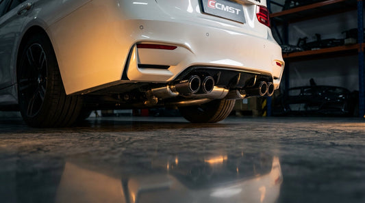 BMW F30 with M4-style rear bumper and CMST quad carbon-tipped valved exhaust, low rear three-quarter hero