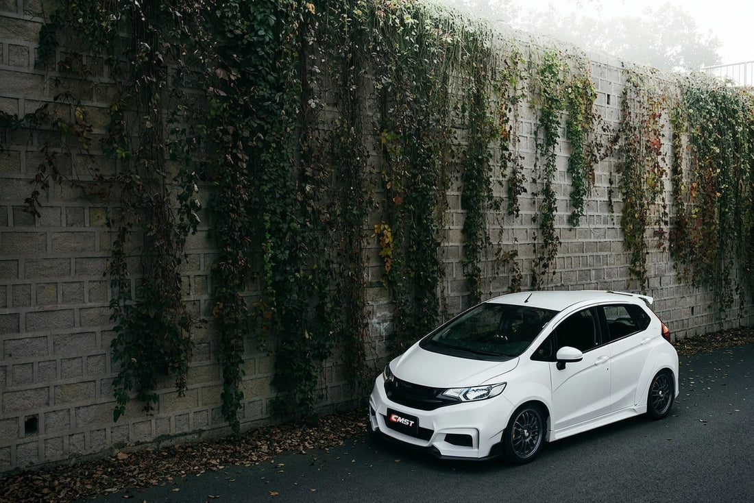Honda Fit GK5 hatchback in midnight blue with CMST widebody kit, wide fenders, low ride height, 3/4 front low angle