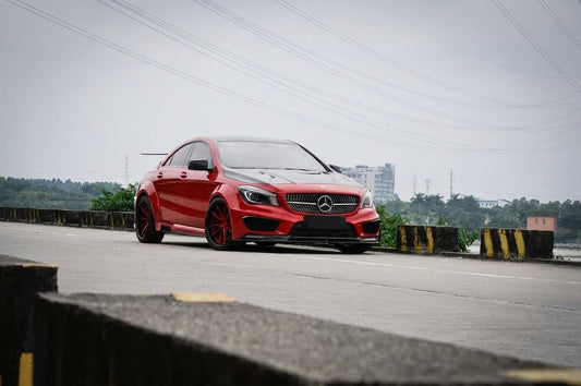 Red Mercedes-Benz CLA C118 widebody wearing a CMST carbon fibre aero kit, front three-quarter low angle in a moody studio