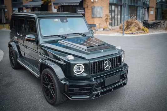 Mercedes-AMG G63 in dark green wearing a CMST dry carbon fibre body kit, front three-quarter low angle in a moody studio
