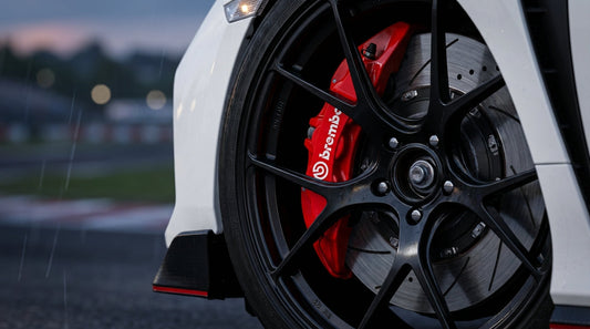 Close-up of a high-performance red Brembo brake caliper and slotted rotor on a Honda Civic Type R for track use.