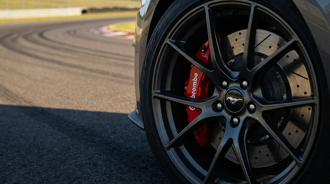 A close-up of a high-performance red big brake kit with slotted rotors installed on a Ford Mustang GT for improved stopping power.