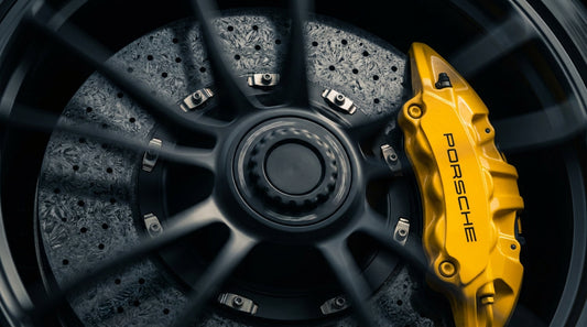 Close-up of a Porsche yellow brake caliper and cross-drilled carbon ceramic rotor on a high-performance Porsche 911 wheel.
