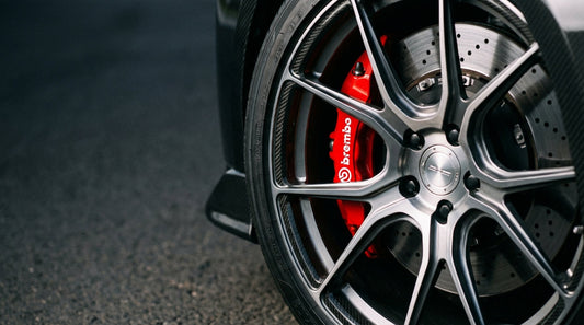 Close-up of a red Brembo brake caliper and performance rotor on a car wheel for a brake pad replacement guide.